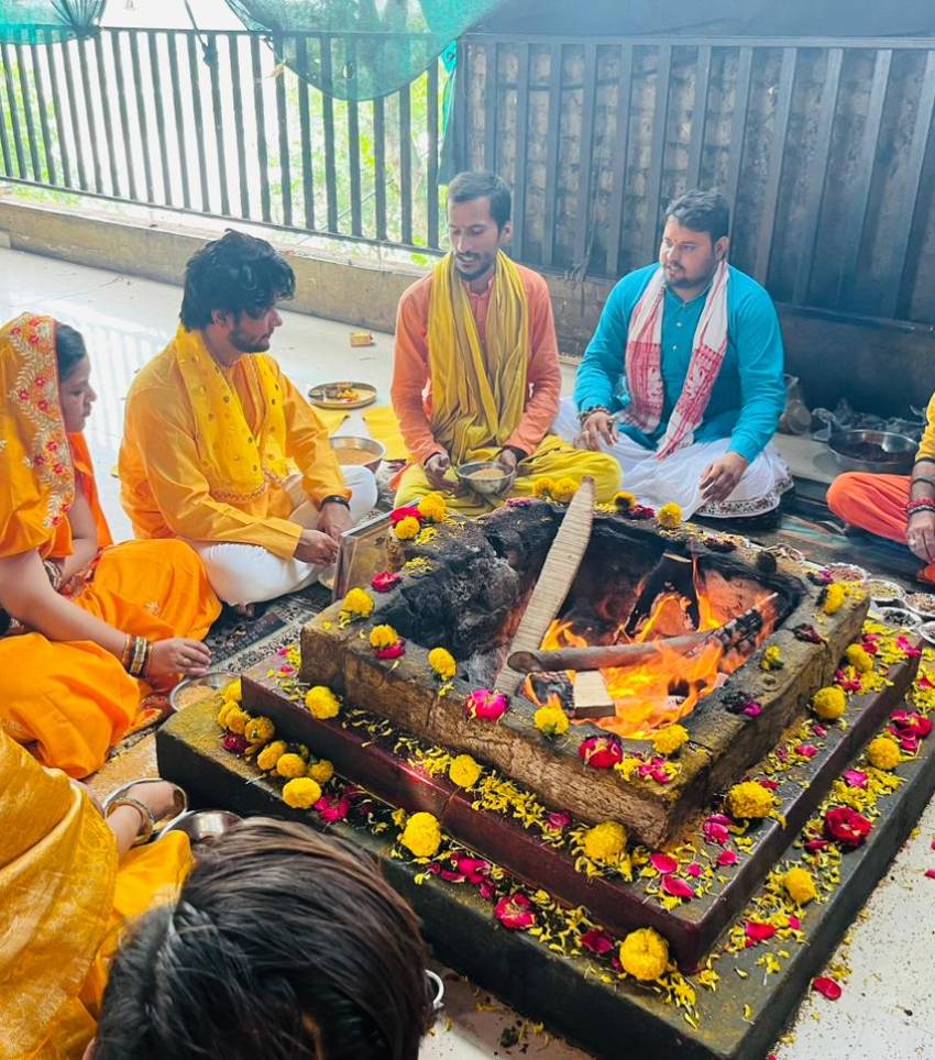 A group of people performing the Baglamukhi Anusthan Puja Vidhi ritual. They are seated in a circle around a central altar adorned with sacred items. Incense smoke fills the air as participants chant prayers and make offerings, invoking the divine energies of Goddess Baglamukhi for protection and empowerment.